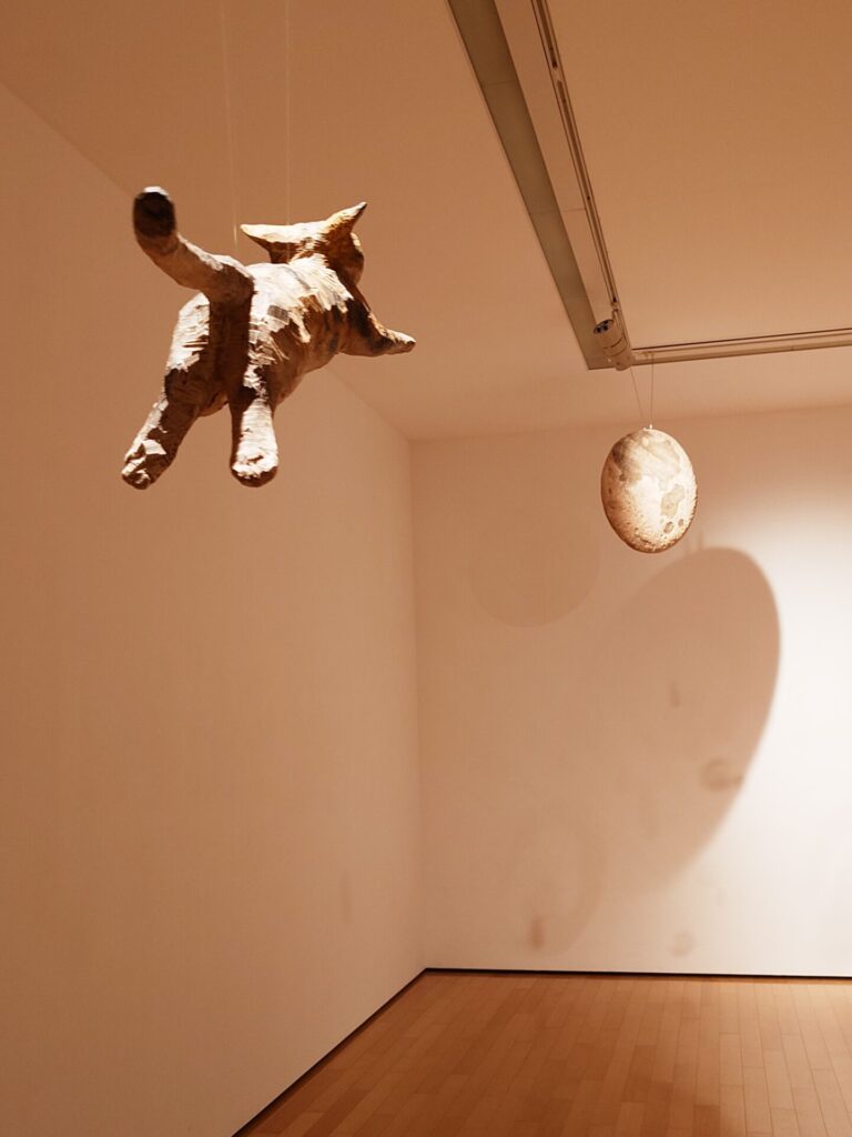 彫刻展の一室で展示されていたクドリャフカ(ライカ犬)の後ろに吊るされていた月をめがけて跳躍する猫の木彫像